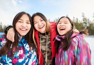 young Native American girls in warm clothing looking at camera and smiling in the winter